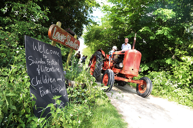 Festival director Matt and a young helper drive the red tractor at Lower Shaw Farm